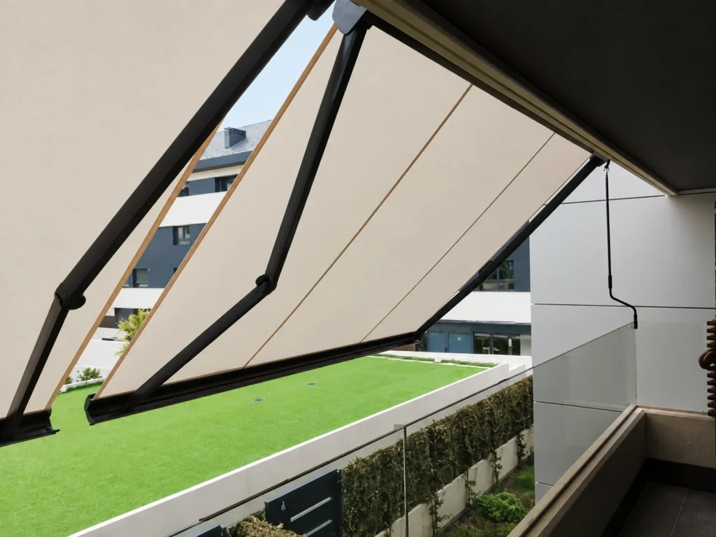 Toldo extensible crema con brazos negros sobre una terraza con césped en Madrid