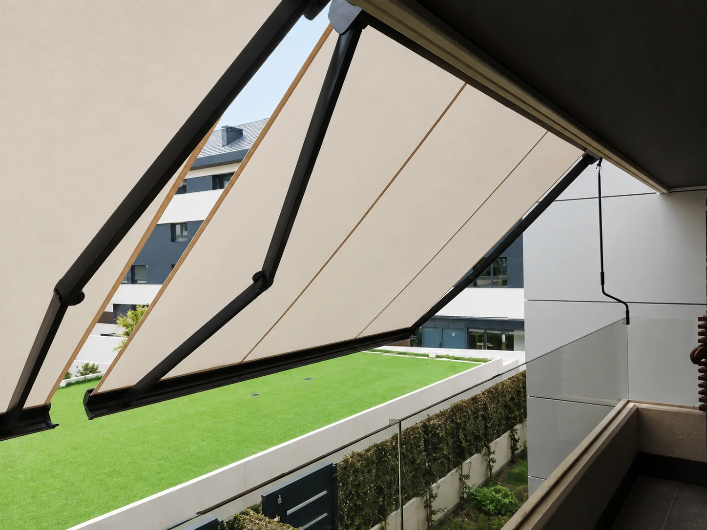 Toldo extensible crema con brazos negros sobre una terraza con césped en Madrid