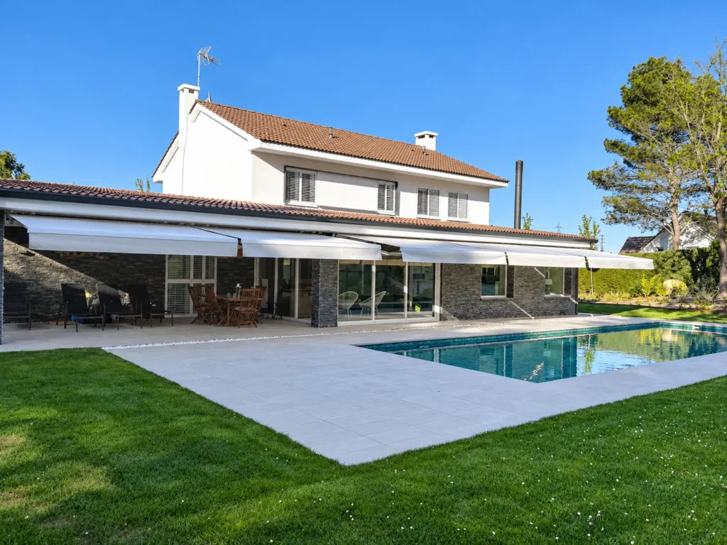 Toldos extensibles blancos en la fachada de una casa con piscina en Madrid