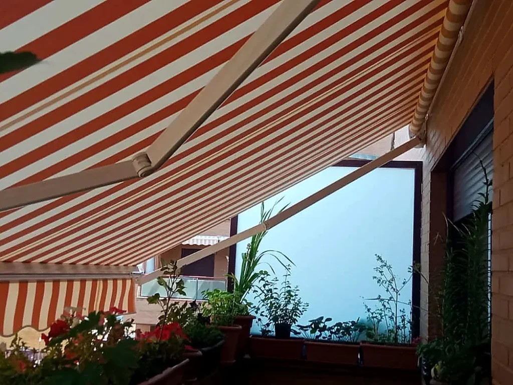 Toldos para terrazas en Madrid: toldo de rayas rojas y blancas con jardineras