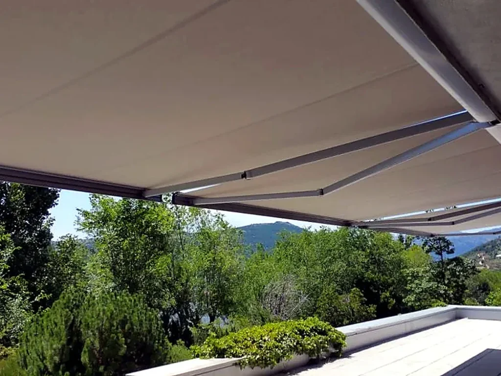 Toldos para terrazas en Madrid: toldo extensible claro sobre terraza con vegetación