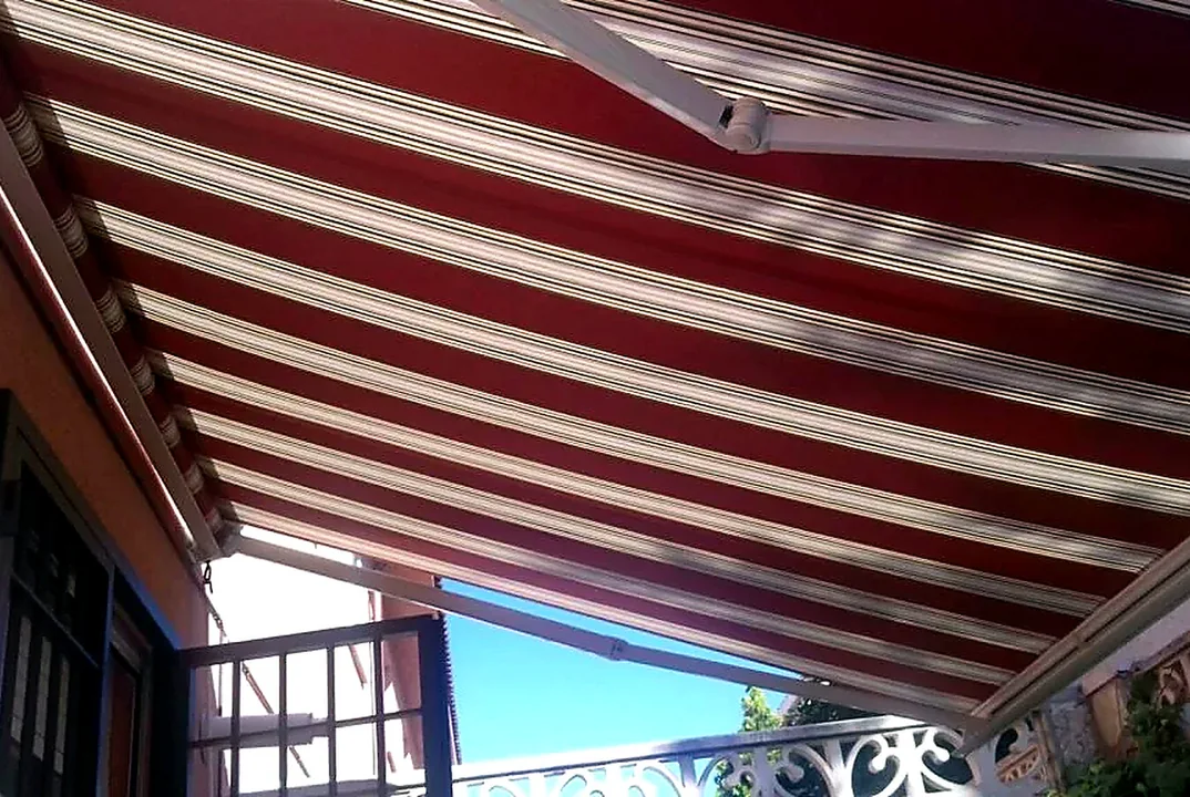 Toldos para terrazas en Madrid: toldo de rayas granate y blancas sobre terraza