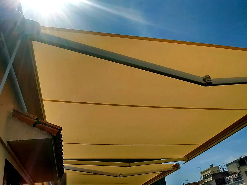 Toldos para terrazas en Madrid: toldo extensible amarillo a pleno sol sobre terraza