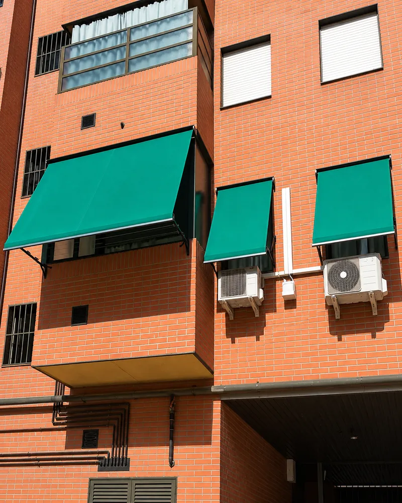 Toldos verdes en ventanas de un edificio de ladrillo en Madrid