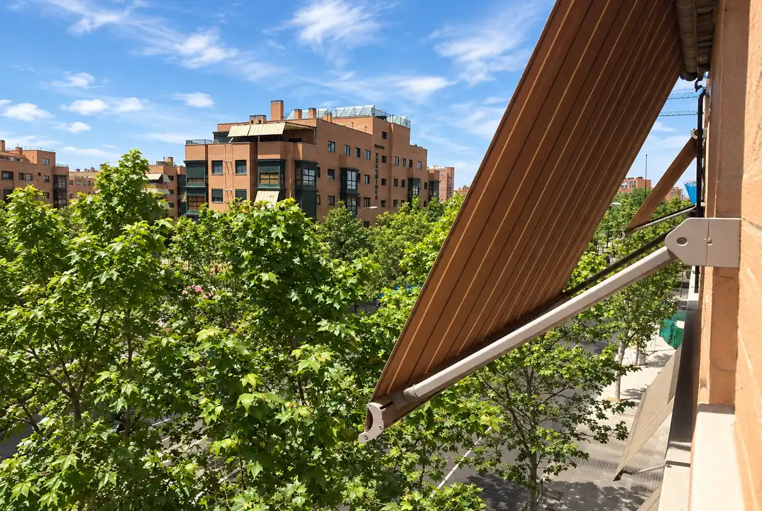 Toldo de color marrón instalado en una ventana de un edificio de viviendas