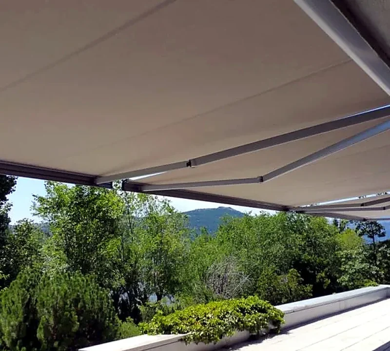 Toldos para terrazas en Madrid: toldo extensible claro sobre terraza con vistas a la sierra
